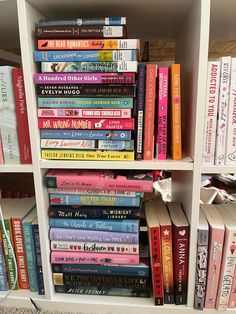 a white book shelf filled with lots of books on top of carpeted flooring