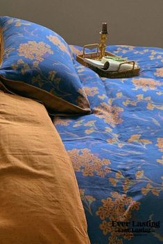 a bed with blue and yellow sheets, pillows and a phone on top of it