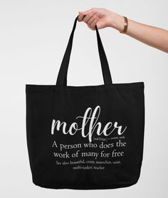 a person holding a black tote bag with the words mother written on it,