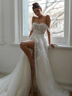 a woman in a wedding dress sitting on a window sill with her legs crossed