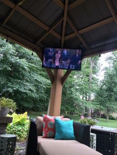 a tv is mounted to the side of a gazebo with couches and pillows