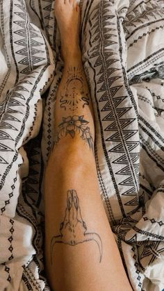 a person laying on top of a bed with a tattoo on their arm and leg