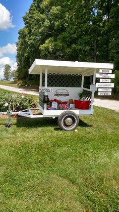 a food truck parked on the side of a road in front of some trees and bushes