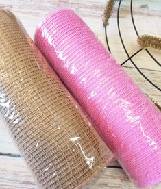 two rolls of pink yoga mat sitting next to each other on a wooden table with dried plants