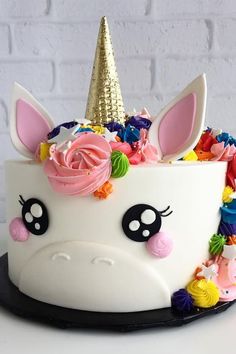 a birthday cake decorated with an unicorn's face and flowers