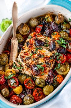 a pan filled with meat and vegetables on top of a blue plate next to a wooden spoon