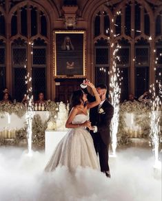 a bride and groom are standing in the clouds at their wedding reception with sparklers all around them