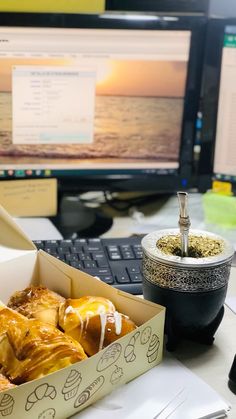 a box filled with pastry sitting on top of a desk next to a computer monitor