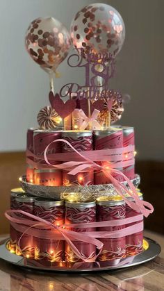 a three tiered cake with balloons on top is decorated in pink and gold colors