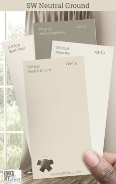 a hand holding three swatches of neutral paint colors with the words sw neutral ground on them