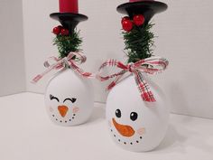 two decorated christmas balls with red candles on them and one has a snowman face painted on it