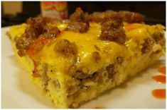 a piece of breakfast casserole on a white plate with orange sauce and meat