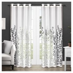 the curtains in this living room are white and grey with black flowers on them,