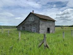 an old wooden house in the middle of a field