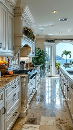 a large kitchen with marble counter tops and white cabinets, along with an arched window overlooking the ocean