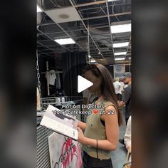 a woman standing in front of a display case holding a piece of paper with the words hot art directors on it