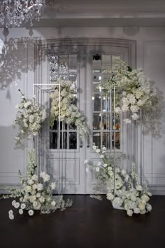 white flowers and greenery on display in front of a door with chandelier