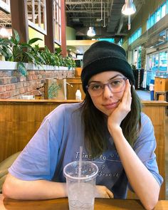 a woman sitting at a table with a drink in front of her