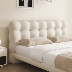 a white bed with pillows on it in a room