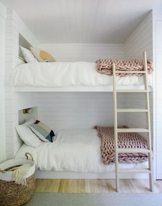 two bunk beds in a small room with white walls and wood flooring on the bottom level