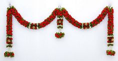 red and white flowers are attached to the side of a wall with two bells on it