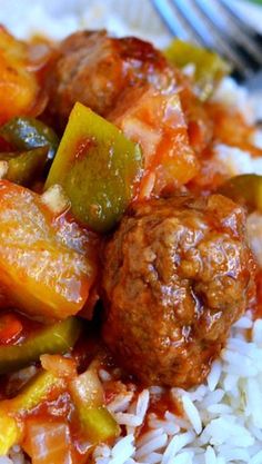 meatballs and vegetables are served over rice on a plate with a fork next to it