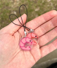 a hand holding a pink and red glass pendant with an elephant on it's side