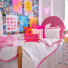 a bed with pink and white sheets, pillows and pictures on the wall behind it