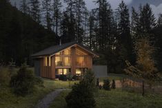 a cabin in the woods at night with its lights on and windows lit from inside