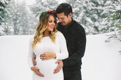 a pregnant couple standing in the snow