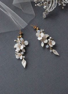 the bride's earrings are adorned with white flowers and pearls