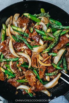 beef and asparagus stir fry in a wok with chopsticks on the side