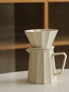 a white coffee pot sitting on top of a table