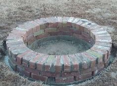 a brick fire pit sitting in the middle of a field