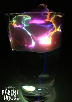 a glass filled with liquid sitting on top of a black table next to a lit candle