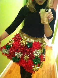 a woman taking a selfie wearing a skirt made out of red and gold poinsettis