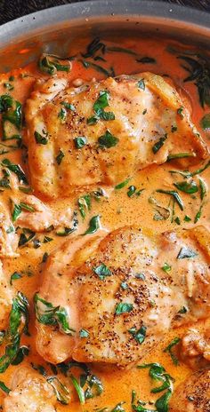 some chicken is cooking in a pan with sauce and herbs on top, ready to be eaten