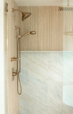 a bathroom with marble walls and flooring next to a walk in shower head mounted on the wall