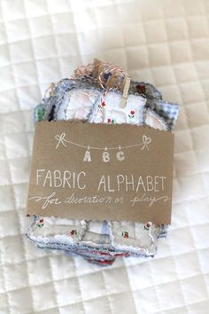 fabric alphabets are displayed on top of each other in small packages with a tag hanging from them