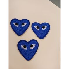 three blue heart shaped patches with eyes on them