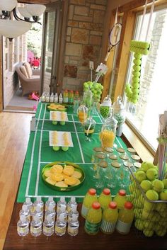 the table is set up for a tennis themed party with drinks, snacks and desserts