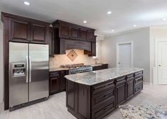 a large kitchen with granite counter tops and dark wood cabinets, along with stainless steel appliances