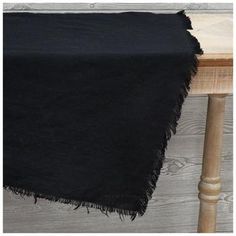 a black table cloth on top of a wooden table next to a white chair and wood planks