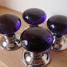 three purple glass knobs sitting on top of a wooden table