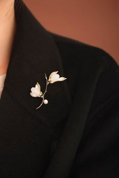 a close up of a person wearing a black jacket with a white flower brooch on it