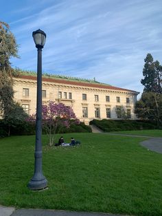 two people sitting on the grass under a lamp post