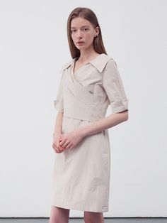 This product is a draped wrap shirt dress that elegantly combines tailored elements with a soft, feminine drape. The dress features a pronounced collar and a V-neckline, leading into a wrap front that ties at the waist, creating a figure-flattering silhouette. Its cuffed short sleeves add a structured detail to the otherwise fluid design. - The wrap style allows for an adjustable fit, catering to various body shapes.- Crafted from a light fabric, the dress is comfortable and suitable for day-long wear.- Its knee-length hem makes it versatile for both office environments and casual outings.- The draped design not only adds elegance but also ensures the dress moves beautifully with the wearer. Fitted V-neck Belted Dress For Daywear, Spring V-neck Belted Work Dress, Fitted Wrap V-neck Dress, Spring Wrap Midi Dress, Chic Wrap Midi Dress For Daywear, Chic Short Sleeve V-neck Dress For Office, V-neck Midi Dress With Folds For Work, Elegant Draped Tie-waist Dress, Chic Draped Wrap Dress For Formal Occasions