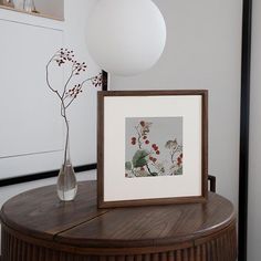 a vase with some flowers and a picture frame on a table next to a lamp