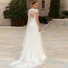 a woman in a wedding dress standing on a stone walkway with her back to the camera