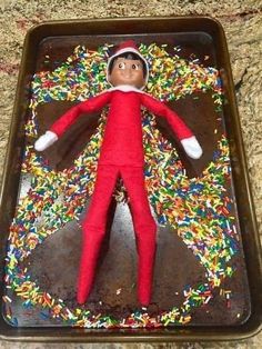 an elf with sprinkles on his head and arms is in a tray